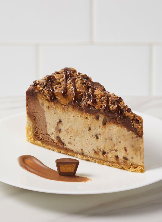 A slice of Reese's Peanut Butter Cheesecake, garnished with a mini Reese's Peanut Butter Cup